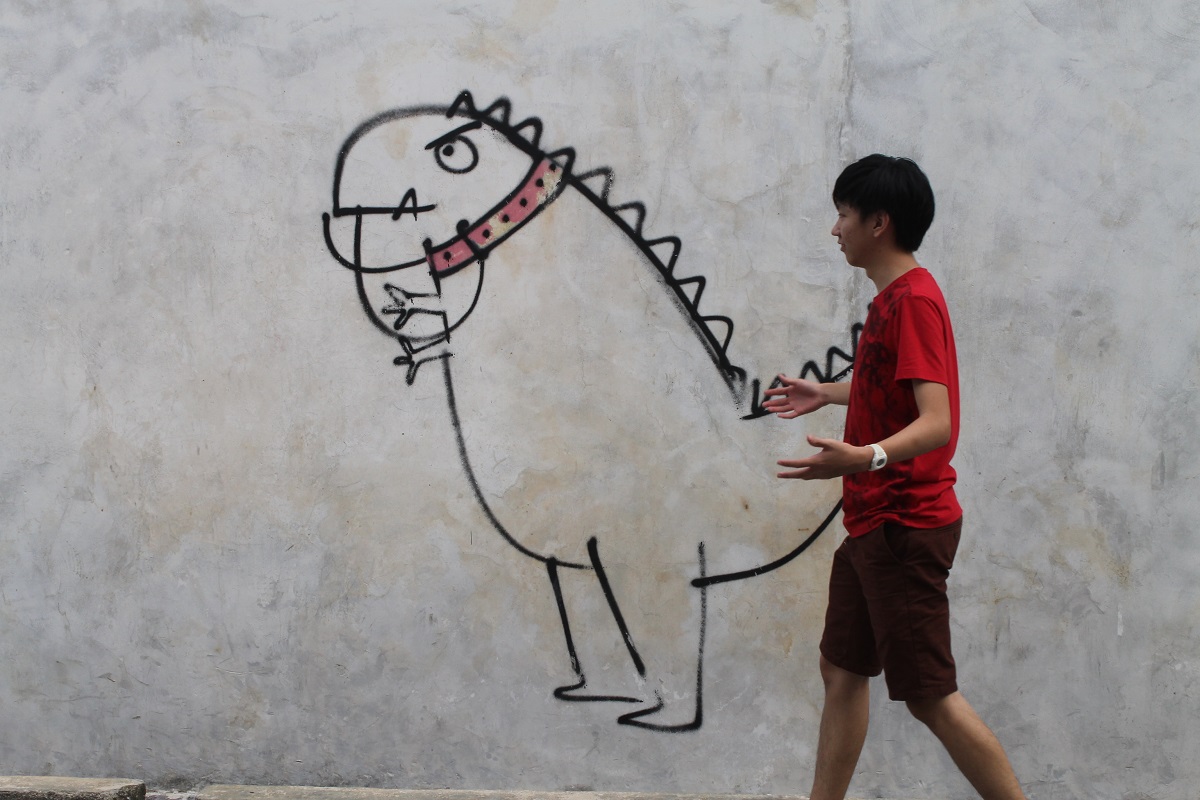Tiew Kee Hui with a dinosaur painted on a wall